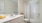 large bathroom with white granite countertop, large mirror, toilet and tub shower